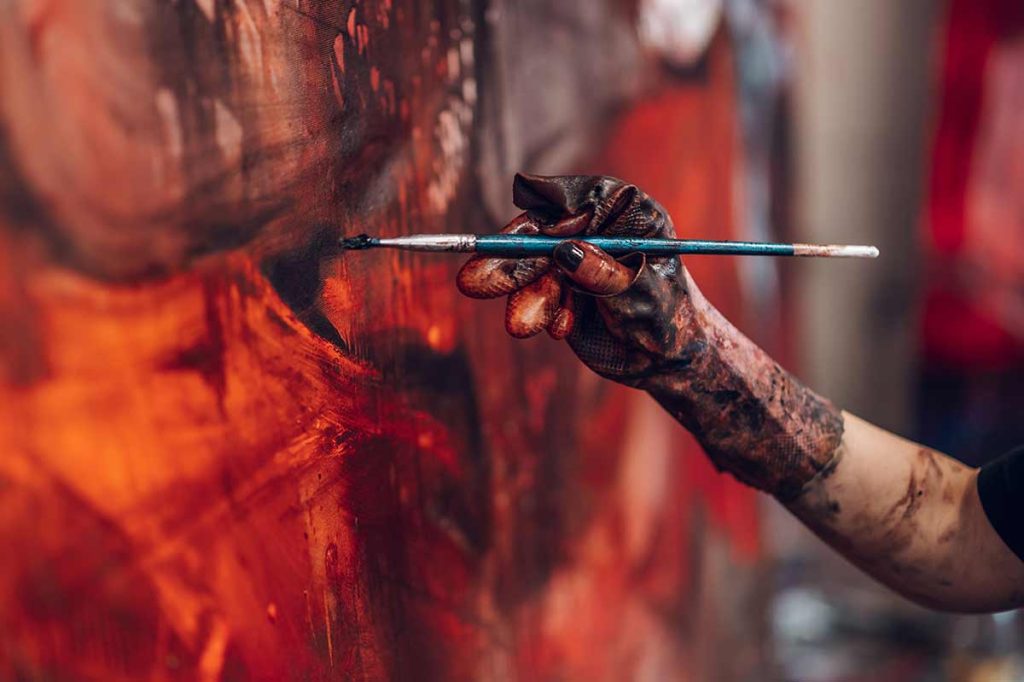 Pittori contemporanei emergenti mentre lavorano su tela con colore ad olio in studio